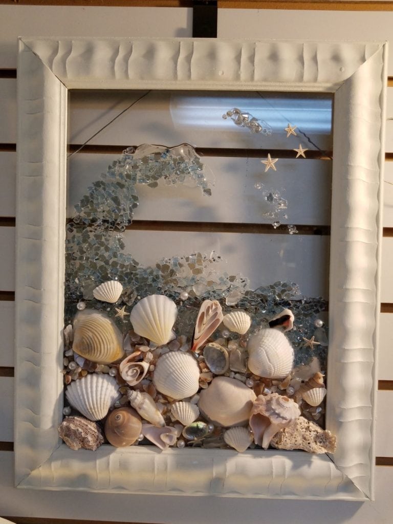 Shell wave on glass. • This local artisan has many pieces in our store.  I am sharing my favorite. This piece measures 14"x18". Beautiful shells in resin to simulate a wave. She also has alot of pieces where she incorporates mermaids.