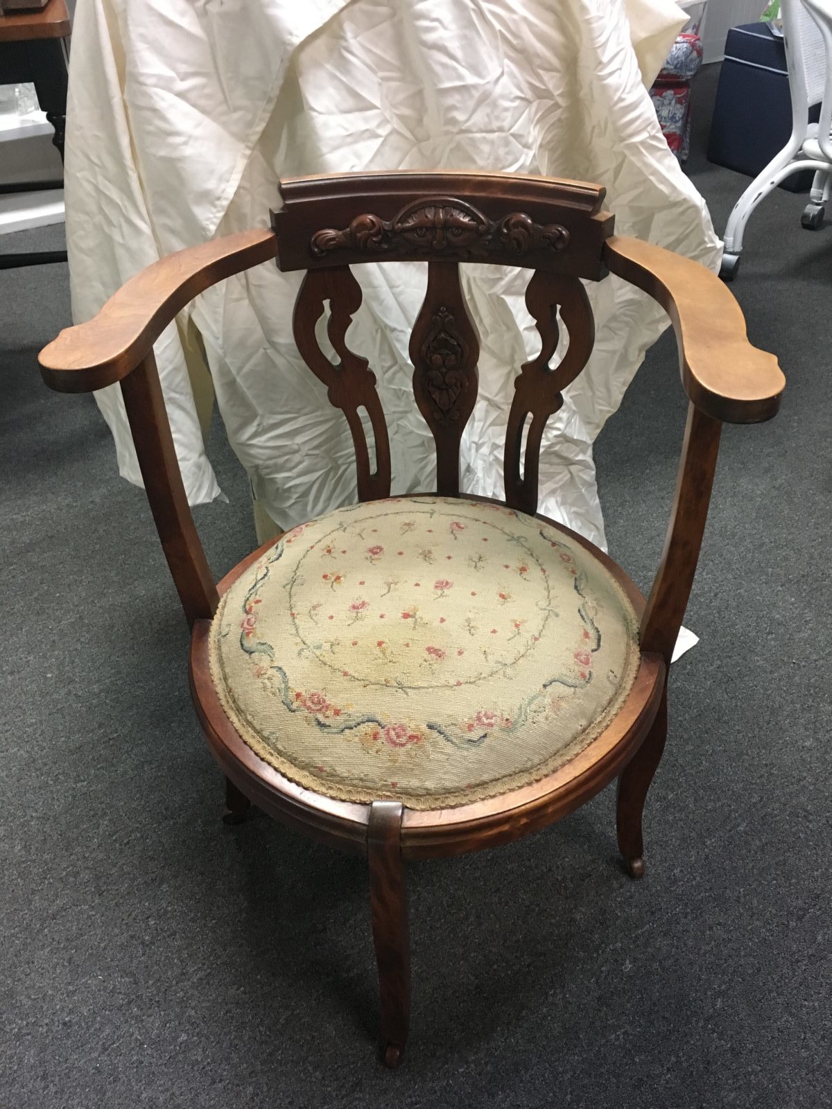 Antique Carved Chair • Antique chair with a needlepoint cushion features a carved design on the back and a very unique rounded seat. Dark wood offsets the light colored needlepoint cushion for a charming and elegant look anywhere you use this chair.